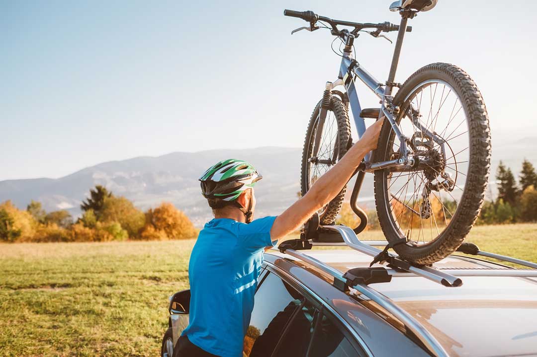 Mountain biker man take of his bike from the car roof