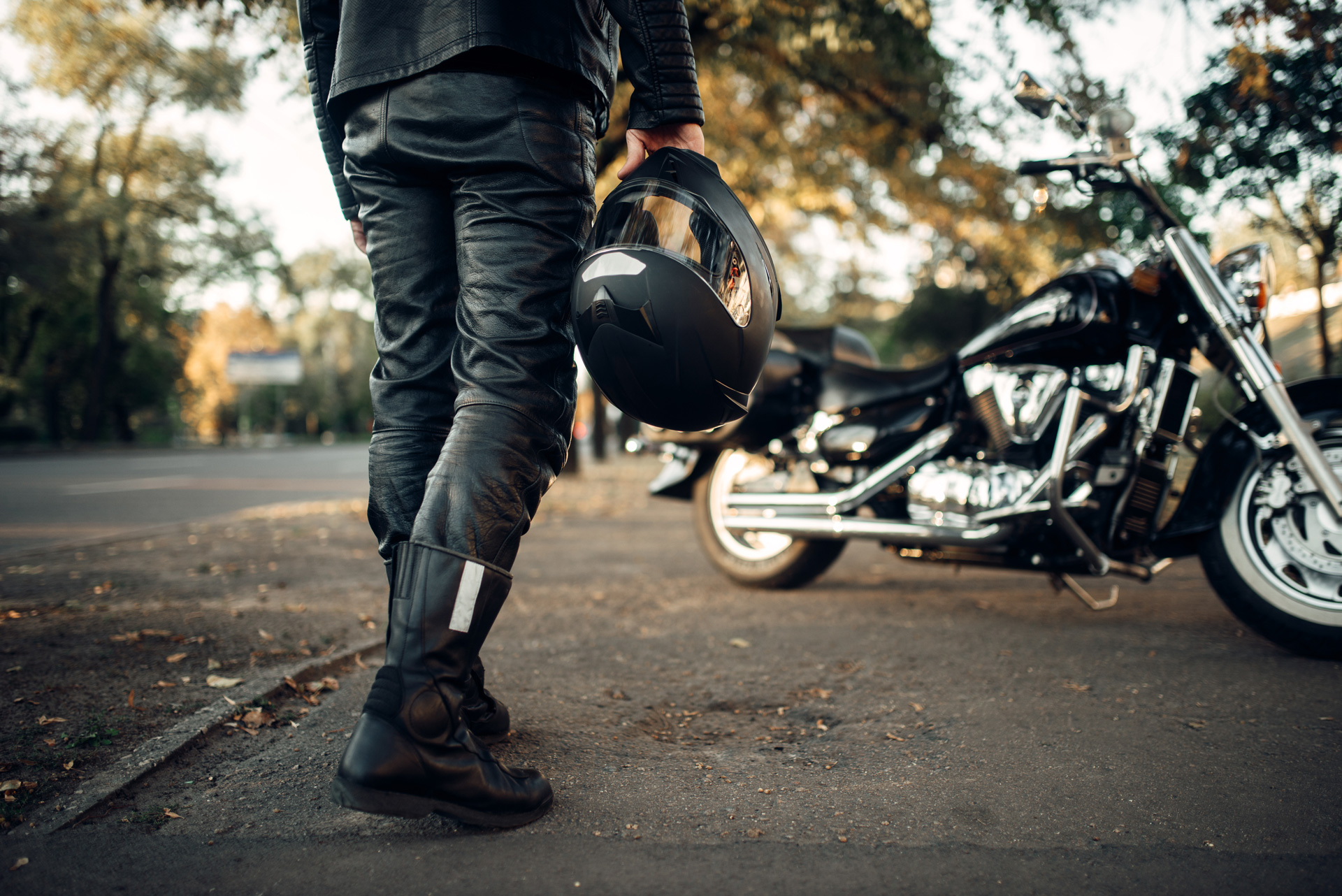 Motorcyclist with helmet in hand goes to chopper