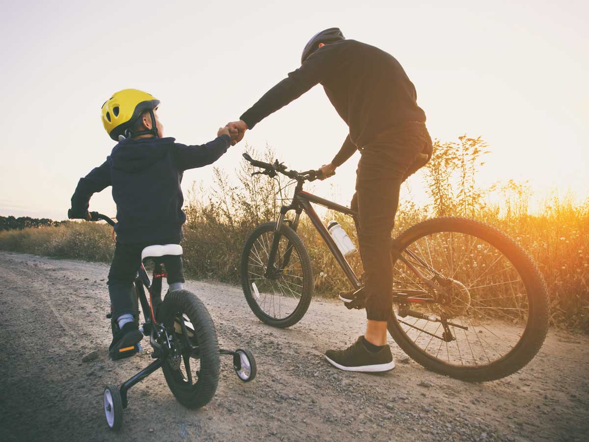 Father and son together are riding bicycles through the pathway