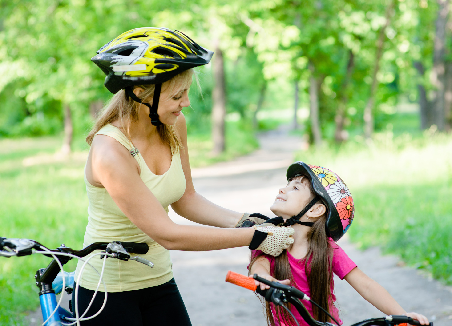 young mother dresses her daughter’s bicycle helmet